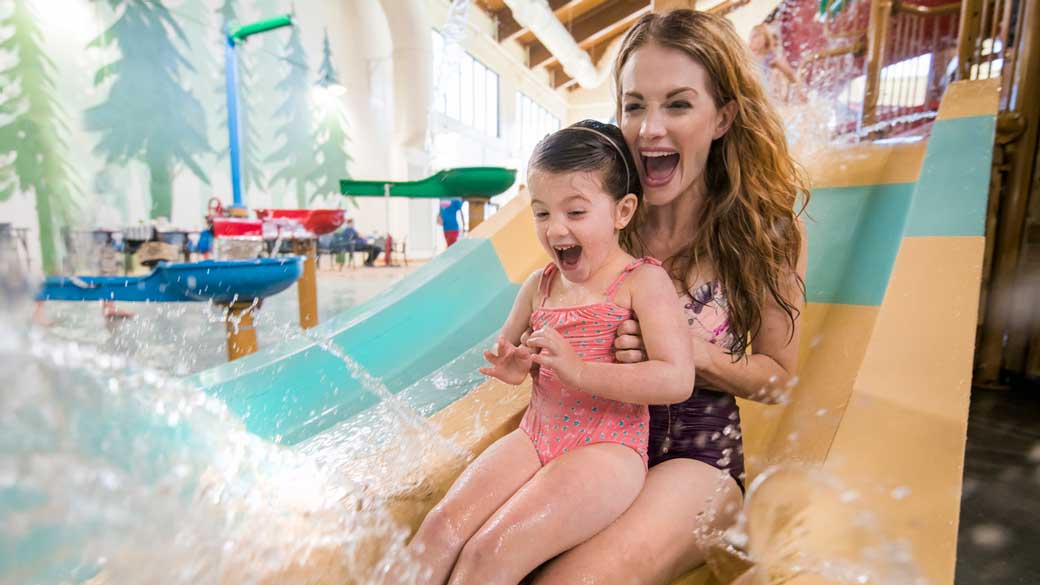 A kid and her mother enjoying a water slide 